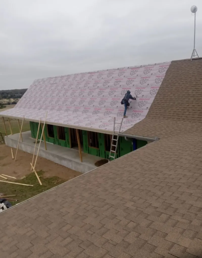 Worker preparing underlayment for a metal roof installation in Round Lake
